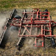 Półzawieszana brona talerzowa Gregoire-Besson w pracy polowej na ściernisku zaczepiona do ciągnika rolniczego