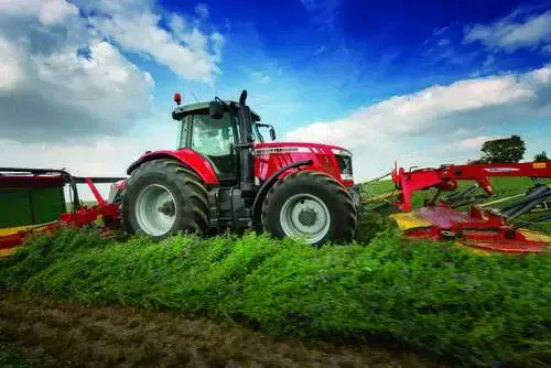 Ciągnik MF z kosiarką Fella Ciągnik Massey Ferguson na polu w trakcie pracy z kosiarką Fella